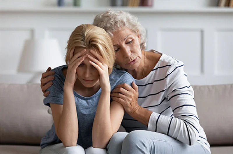 Mother comforting middle-aged daughter dealing with migraine